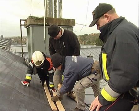 Arbeiter sichern die Platte auf dem Dach des Gebäudes