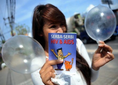 Welt-Aids-Tag auch in Bali: Freiwillige mit einer Broschüre über Aids und aufgeblasenen Kondomen