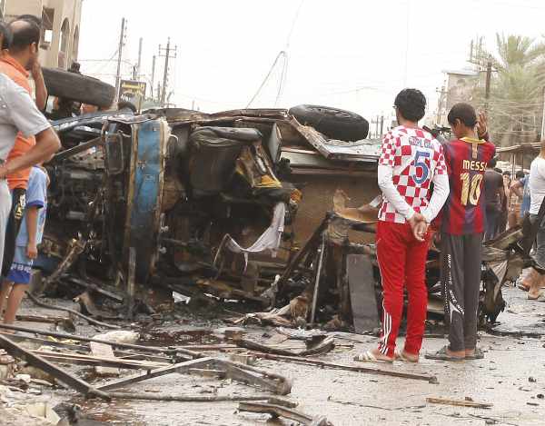 Iraker begutachten ein explodierrtes Auto in Bagdad