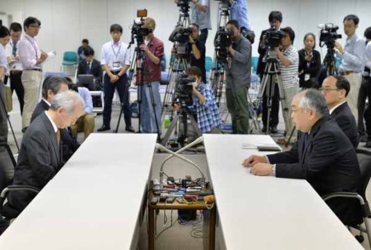 Tepco-Chef Naomi Hirose (l.) bei einem Treffen mit Katsuhiko Ikeda von der Atomaufsichtsbehörde