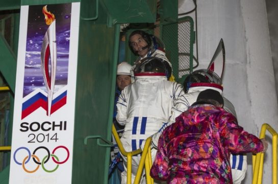 Raumfahrer steigen mit der Olympischen Fackel in die Sojus-Rakete