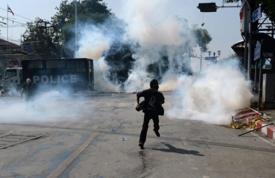 Demonstrant in Bangkok rettet sich vor den Tränengasschwaden