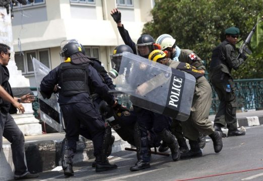 Ausschreitungen in Bangkok - Polizisten transportieren einen durch eine Granate verletzten Kollegen ab