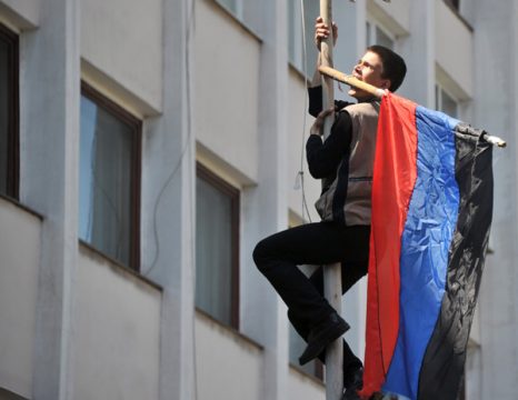 Aktivist trägt russische Flagge an die Spitze eines Gebäudes in Mariupol