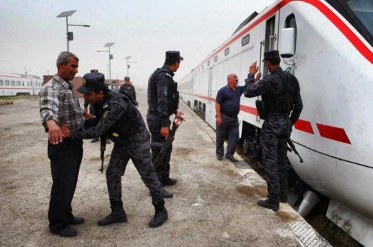 Polizisten führen eine Personenkontrolle in Bagdad durch