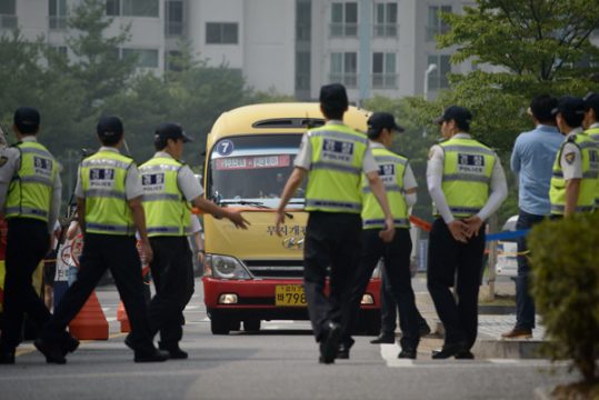 Polizisten vor dem Bus mit überlebenden Schülern der "Sewol"-Katastrophe in Ansan