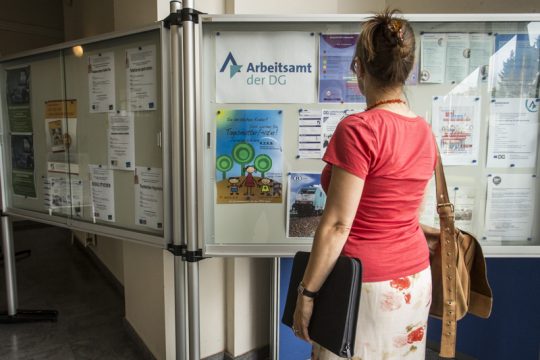 Im Arbeitsamt: Frau vor Wand mit Stellenanzeigen