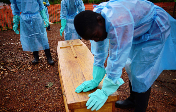 Kailahun, Sierra Leone: Staatsmitarbeiter in Schutzkleidung beerdigen Dr. Modupeh Cole. Er ist der zweite Arzt in dem Land, der an Ebola starb