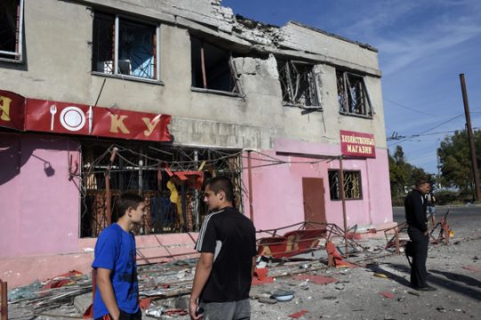 Leute vor einem bei nächtlichen Angriffen zerstörten Gebäude in einem Vorort von Mariupol