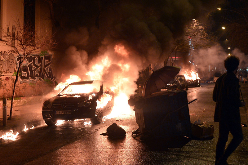 Ausschreitungen in Athen: Mann geht an brennendem Auto vorbei