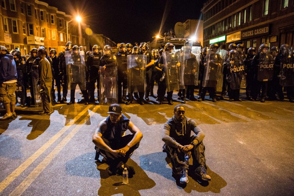 Baltimore kurz vor der Ausgangssperre: Zwei Demonstranten sitzen vor einer Blockade der Polizei