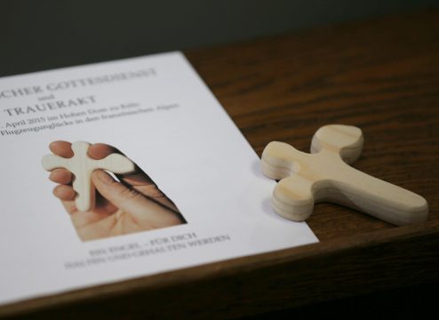 Programmheft der Trauerfeier im Kölner für die Opfer des Germanwings-Absturzes und eines geschnitztes Kreuz