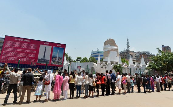 Ein Monat nach Erdbeben: Nepalesen rund um den zerstörten Dharahara-Turm in Kathmandu halten sich die Hände (25.5.)