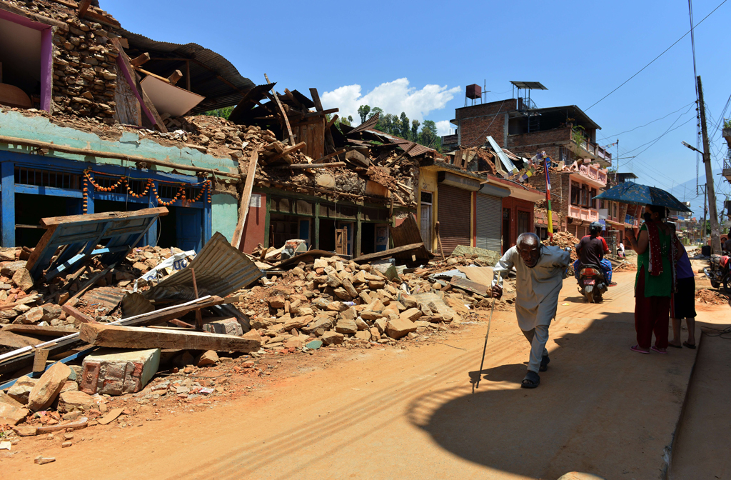 Nepalesen neben zerstörten Häusern in Trishuli im Norden von Kathmandu
