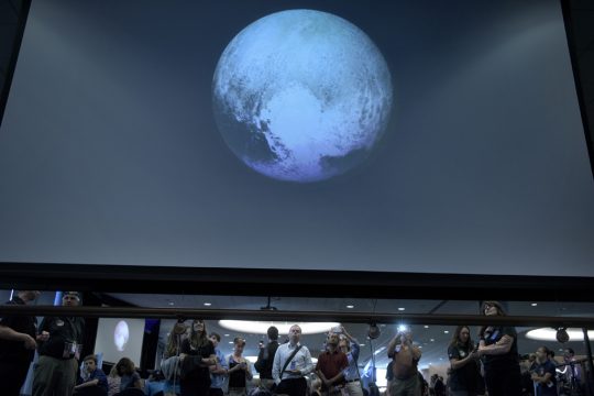 Menschen beobachten Aufnahmen von Pluto