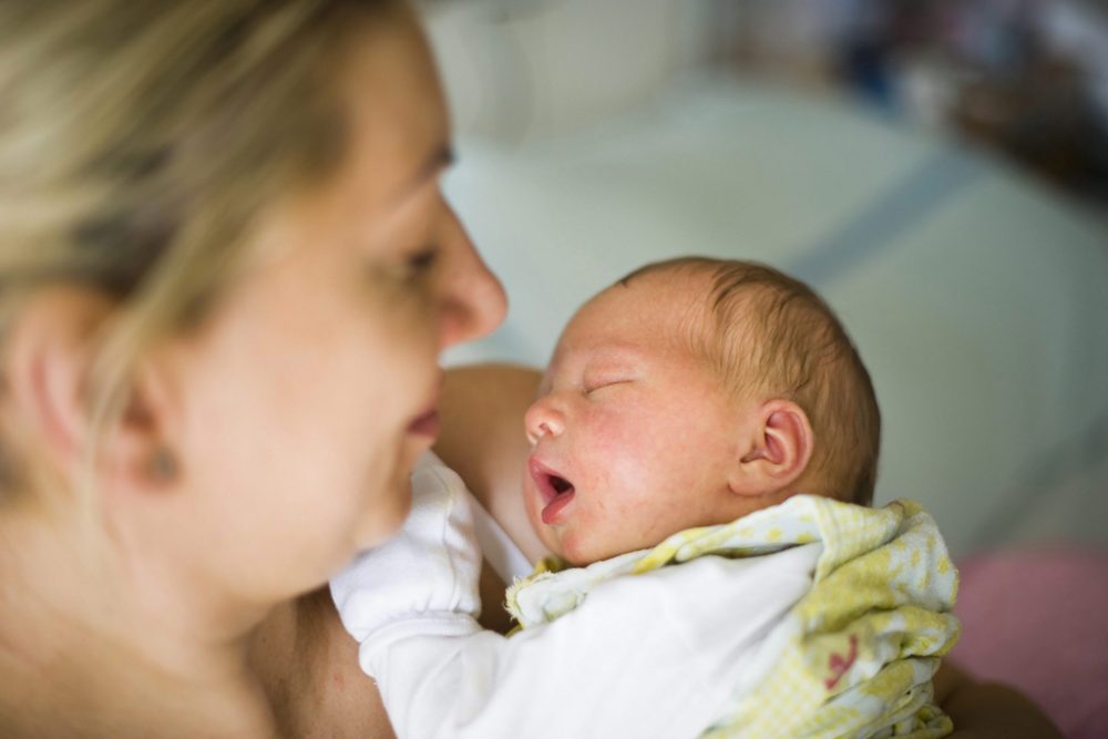 Neugeborenes auf dem Arm der Mutter