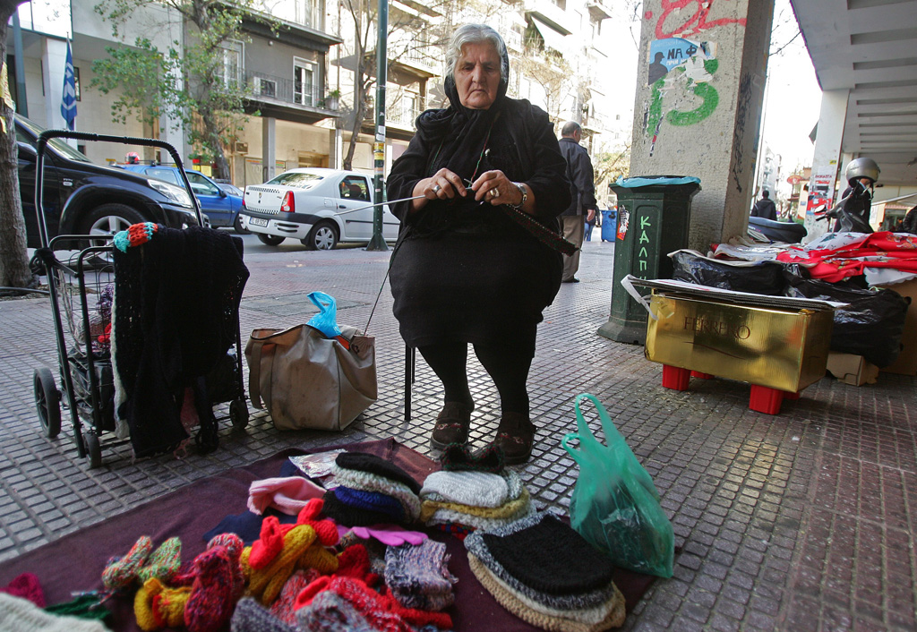 Ältere Griechin strickt und verkauft Mützen in Athen