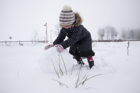 Kleines Mädchen beim Schneemann-Bauen in Jalhay