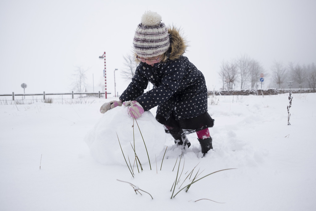 Kleines Mädchen beim Schneemann-Bauen in Jalhay
