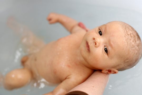 Eine Mutter badet ihr Neugeborenes