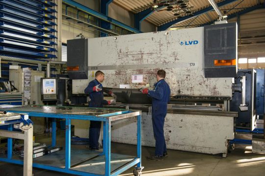 In der Werkstatt von ACM: Zwei Arbeiter beim Kanten von Blechen