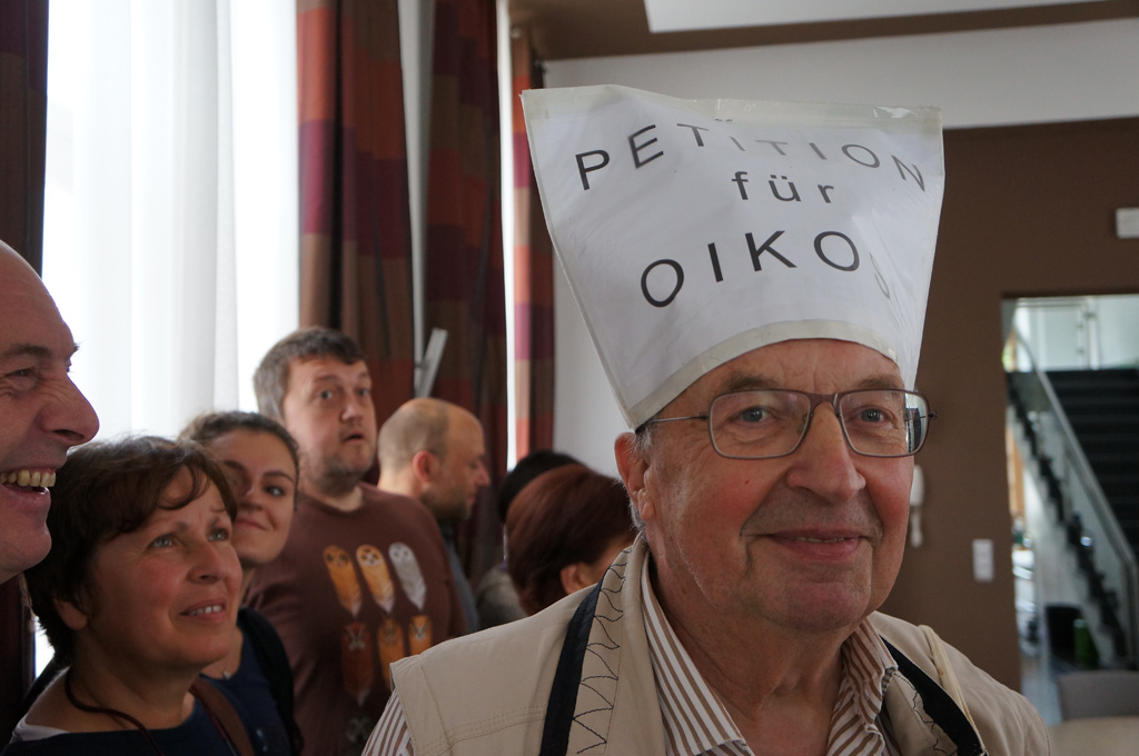 Übergabe eines Bürgertopfes mit zusammengerollten Unterschriftenbögen zur Rettung von Oikos