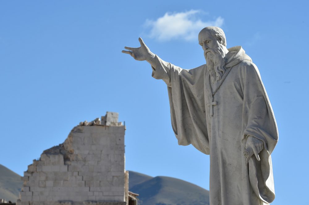 Statue des Heiligen Benedikt vor einem zusammengestürzten Gebäude in Norcia