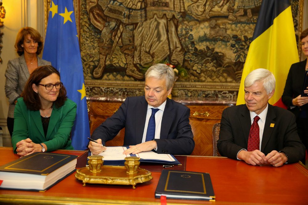 Unter den Augen von EU-Handelskommissarin Cecilia Malmström und Kanadas Botschafter Olivier Nicoloff setzt Außenminister Reynders seine Unterschrift unter das Handelsabkommen