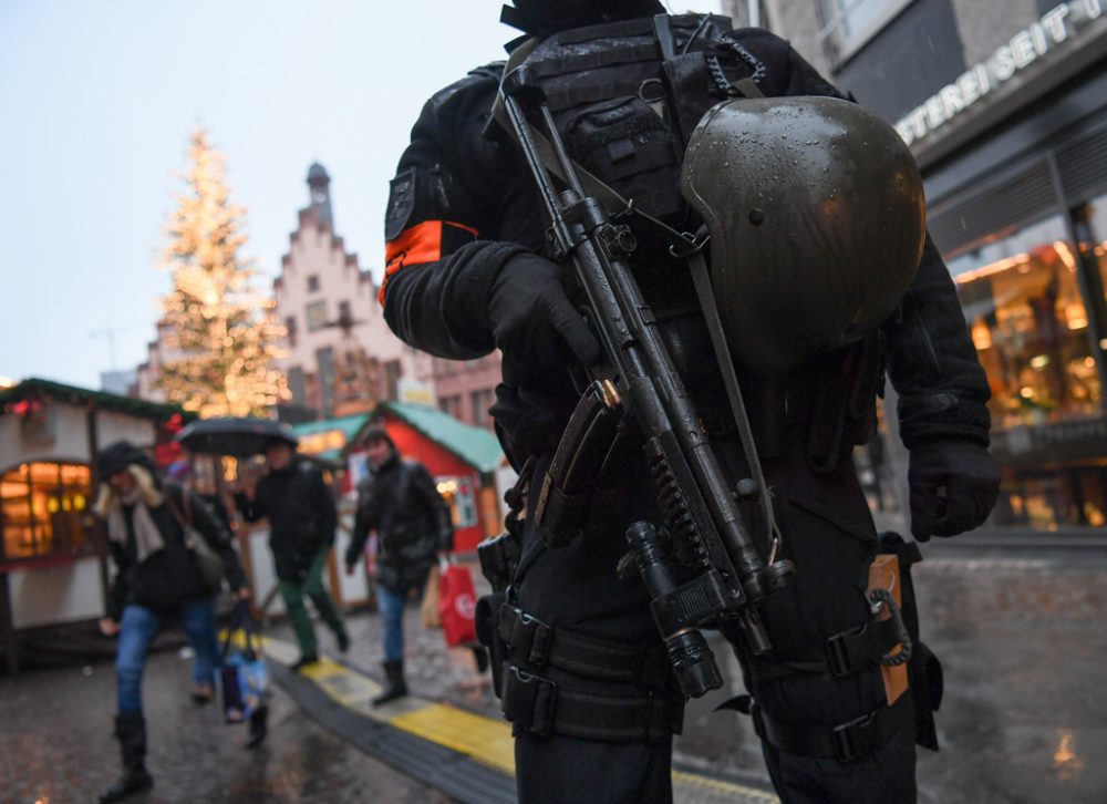 Schwer bewaffneter deutscher Polizist vor einem Weihnachtsmarkt