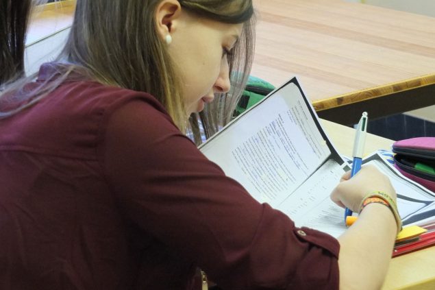 Nina Kessler in der Schulklasse, schreibend am Pult