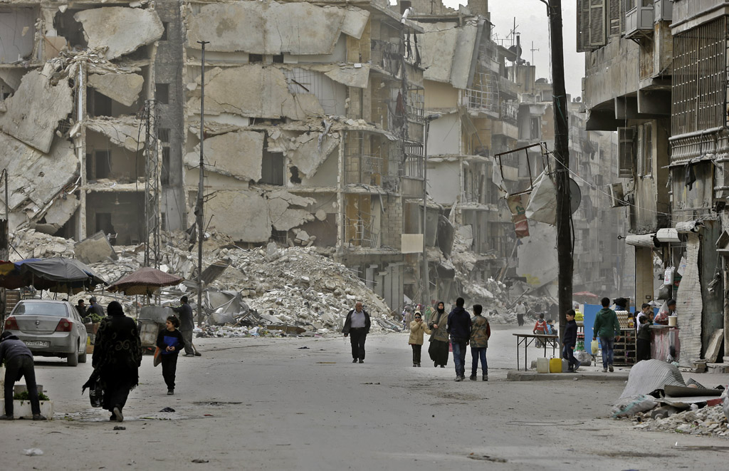 Wenige Menschen gehen durch eine vom Krieg zerstörte Stadt nördlich von Aleppo