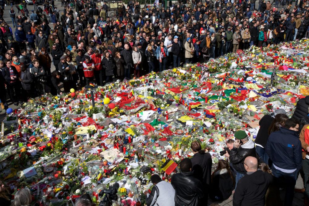 Menschenmenge vor Teppich aus Blumen und Fahnen im Gedenken an die Opfer der Anschläge