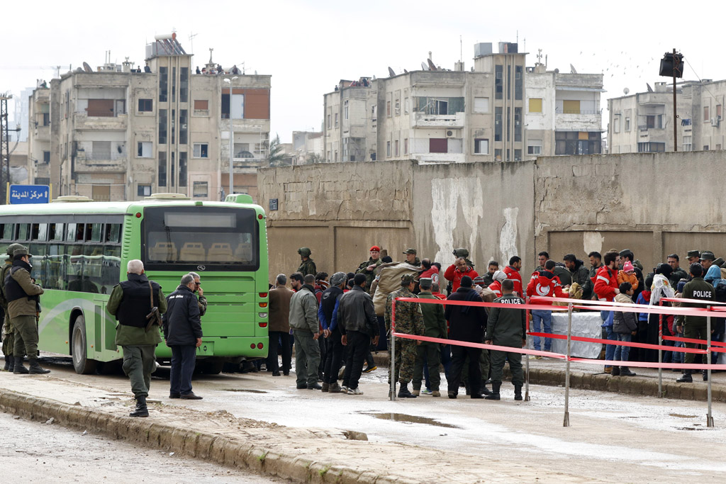 Menschen in Homs stehen an, um in den Bus zu steigen, der sie aus der Stadt bringt