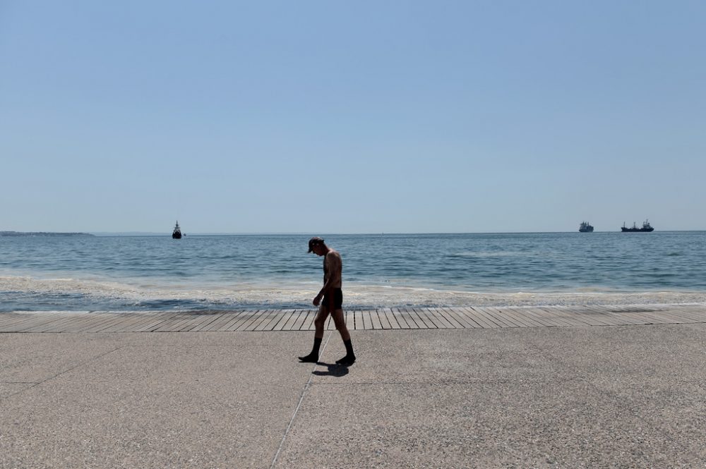 Ein Mann geht mit gesunkenem Kopf am Strand entlang