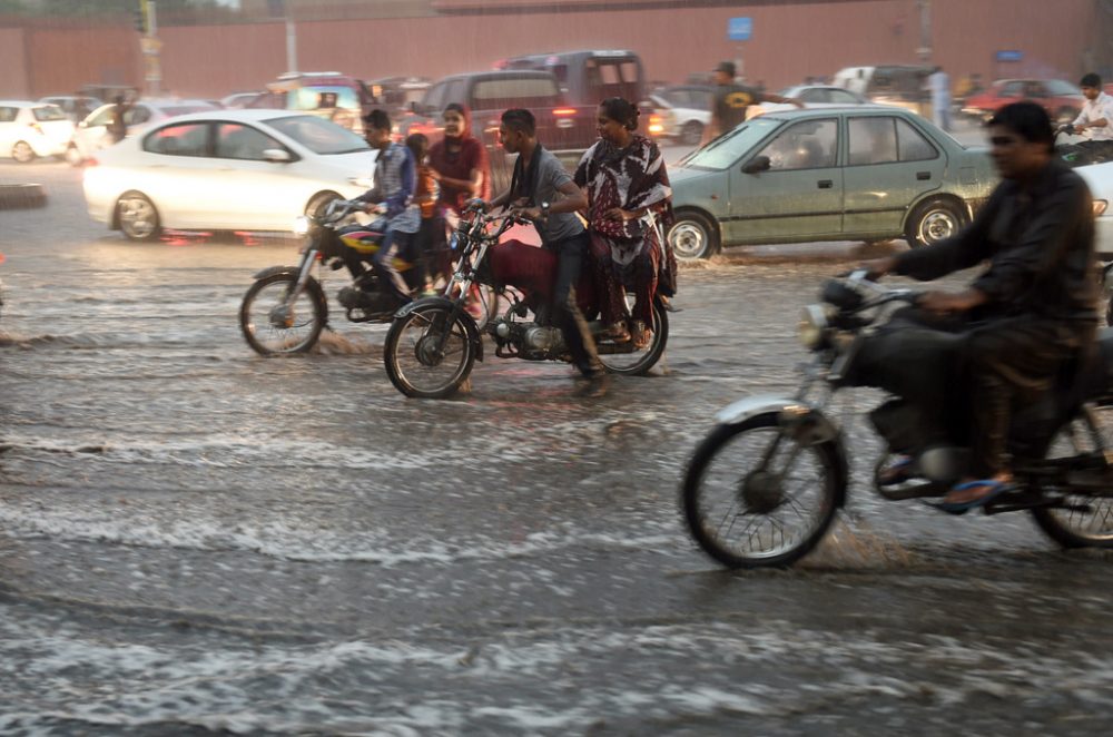 Mopeds fahren in Karachi über überflutete Straßen