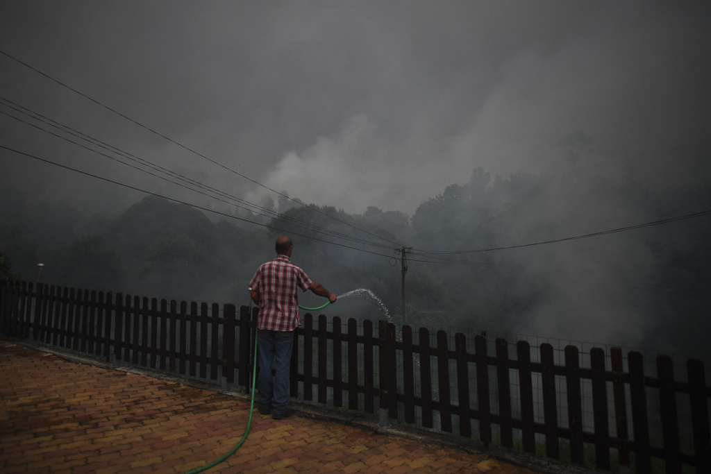 Dorfbewohner in Trespostos kämpft mit Gartenschlauch gegen die herannahenden Flammen