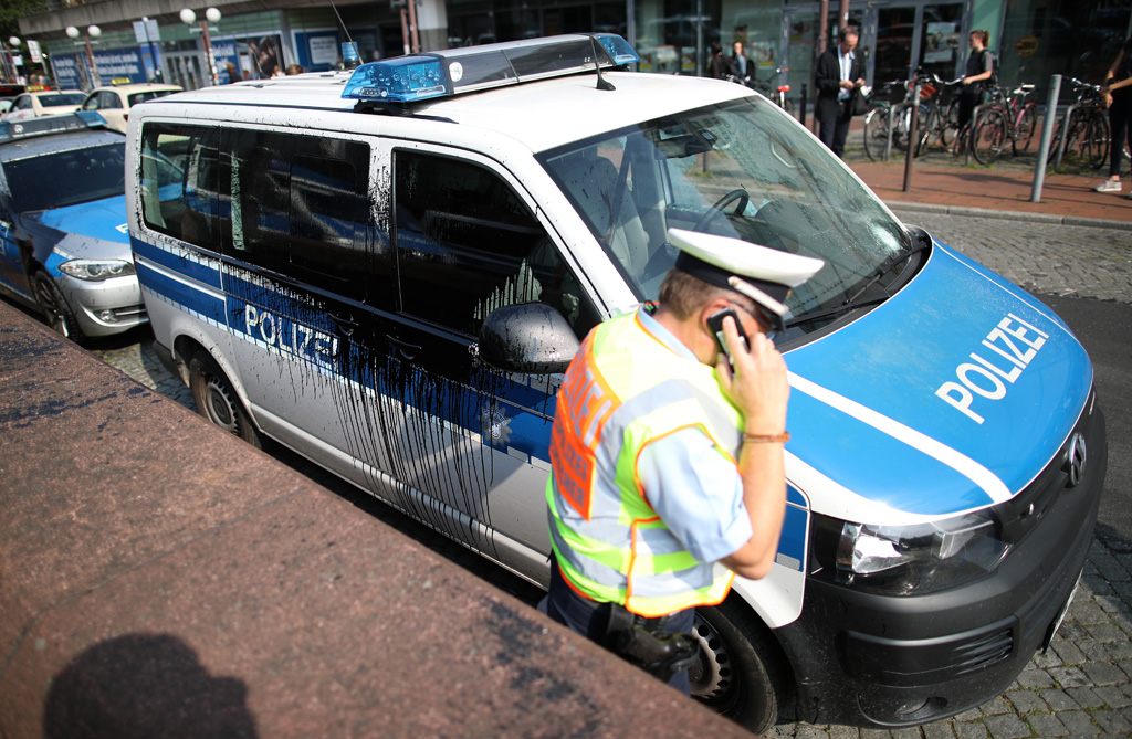 Polizist neben einem mit schwarzer Farbe angegriffenen Polizeiauto in Hamburg (7.7.2017)