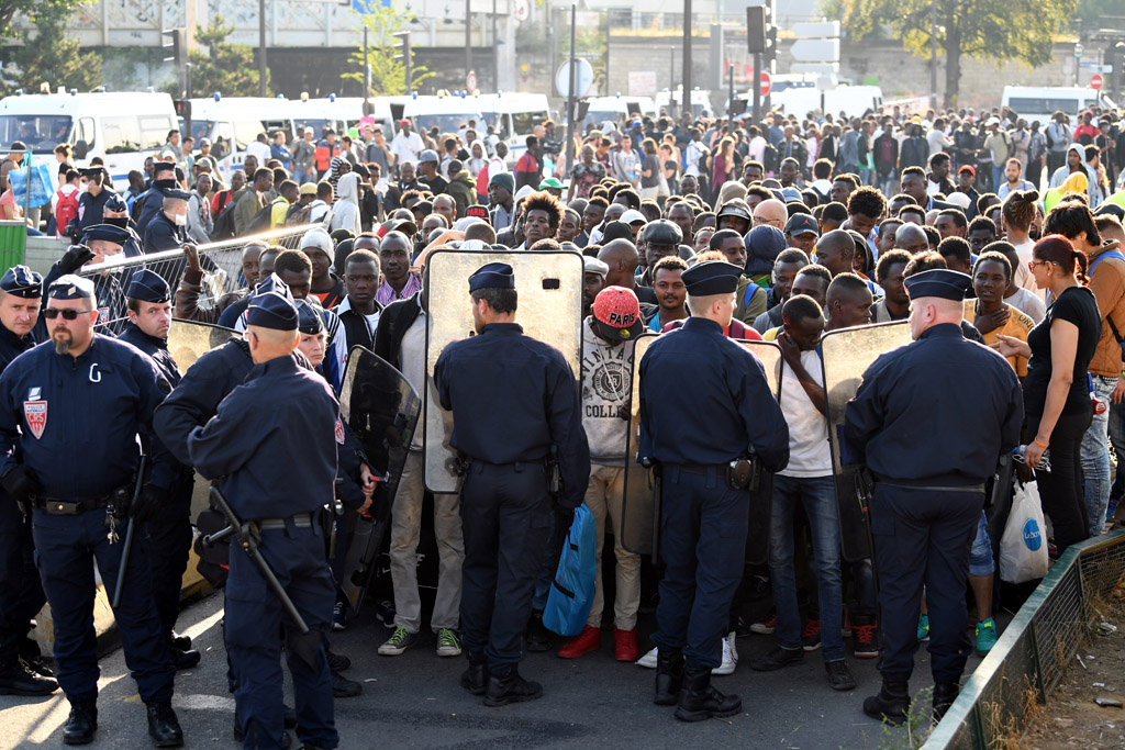 Polizisten bewachen Migranten während der Räumung eines Flüchtlings-Lagerplatzes in Paris (7.7.2017)