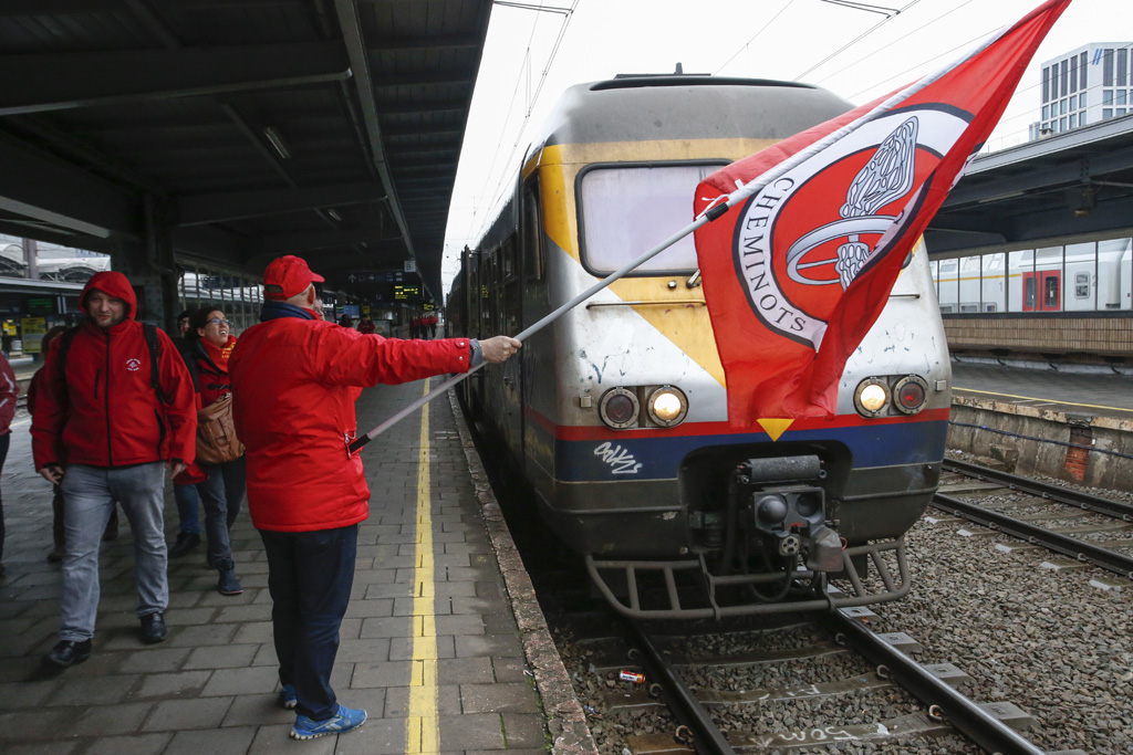 Gewerkschafter schwenkt im Bahnhof eine rote Flagge
