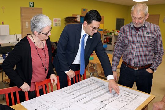 Sozialminister Antoniadis begutachtet gemeinsam mit der zuständigen Gemeindeschöffin Nicole Heinen-Curnel und dem Ameler Bürgermeister Klaus Schumacher die Ausbaupläne der AUBE Amel (Bild: Ministerium der DG)