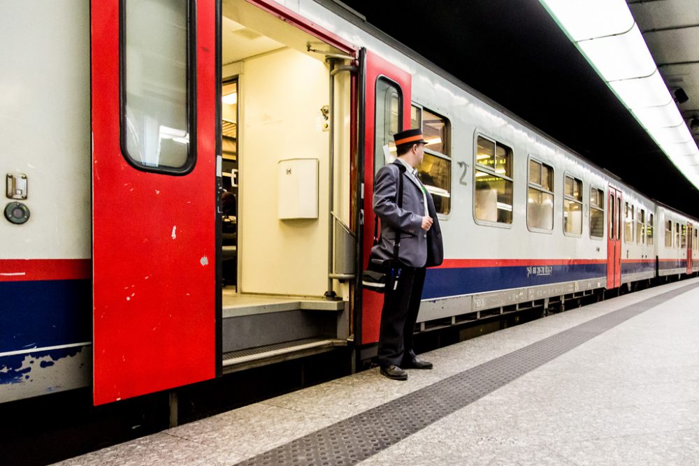 Schaffner vor einem Zug der SNCB