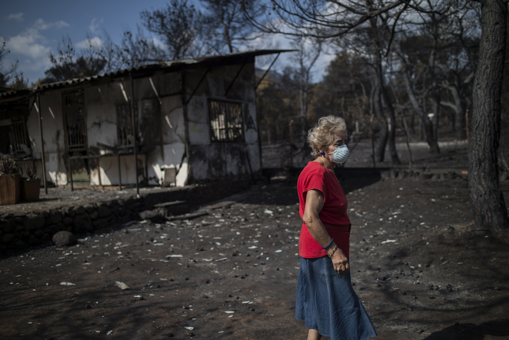 Griechin vor ihrem verbrannten Haus in Neos Voutzas nahe Athen (Bild: Angelos Tzortzinis/AFP)
