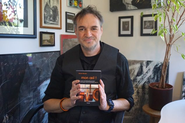 Marzel Maraite mit seinem Buch "mon oeil" (Bild: Stephan Pesch/BRF)