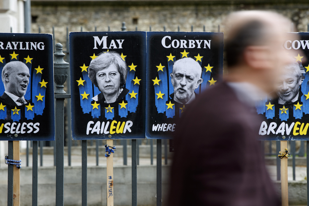 Theresa May und Jeremy Corbyn blicken von Plakaten auf Londons Bürger (Foto: Tolga Akmen / various sources / AFP)