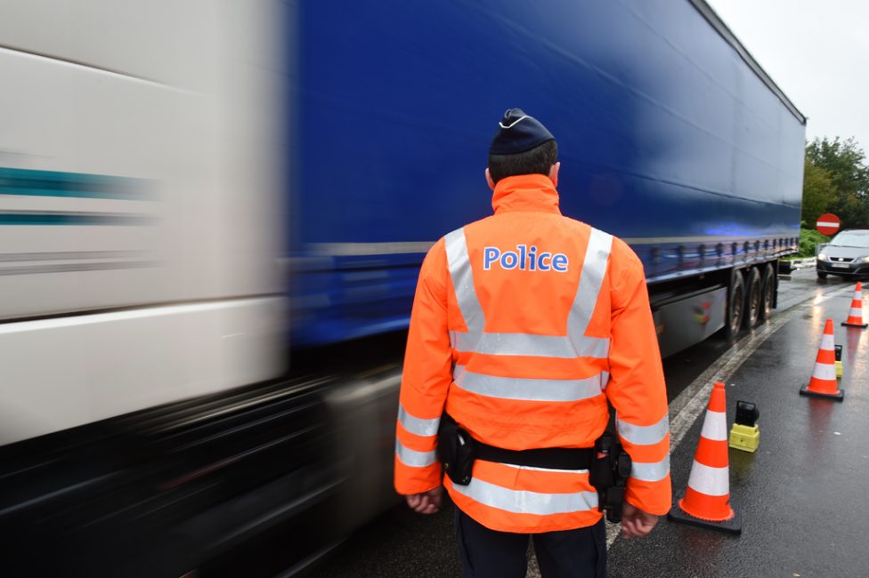 Polizist steht bei Kontrolle neben Lkw