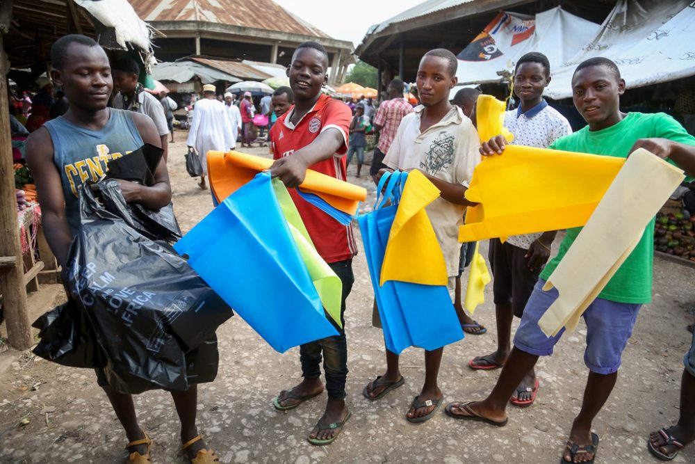 Tansanischer Straßenhändler (l.) verkauft am 31.5.2019 Plastiktüten, während die anderen alternative Tüten in Dar es Salaam anbieten (Bild: Said Khalfan/AFP)