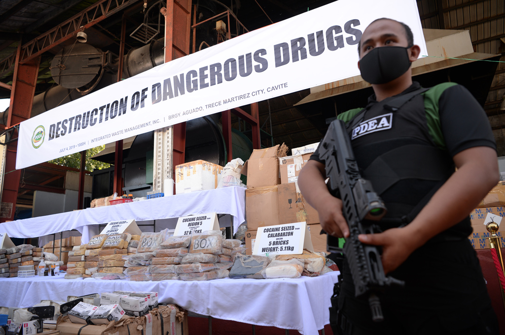 Illustration: Bewaffneter Agent der Philippine Drug Enforcement Agency (PDEA) neben beschlagnahmten Drogen (Bild: Ted Aljibe/AFP)