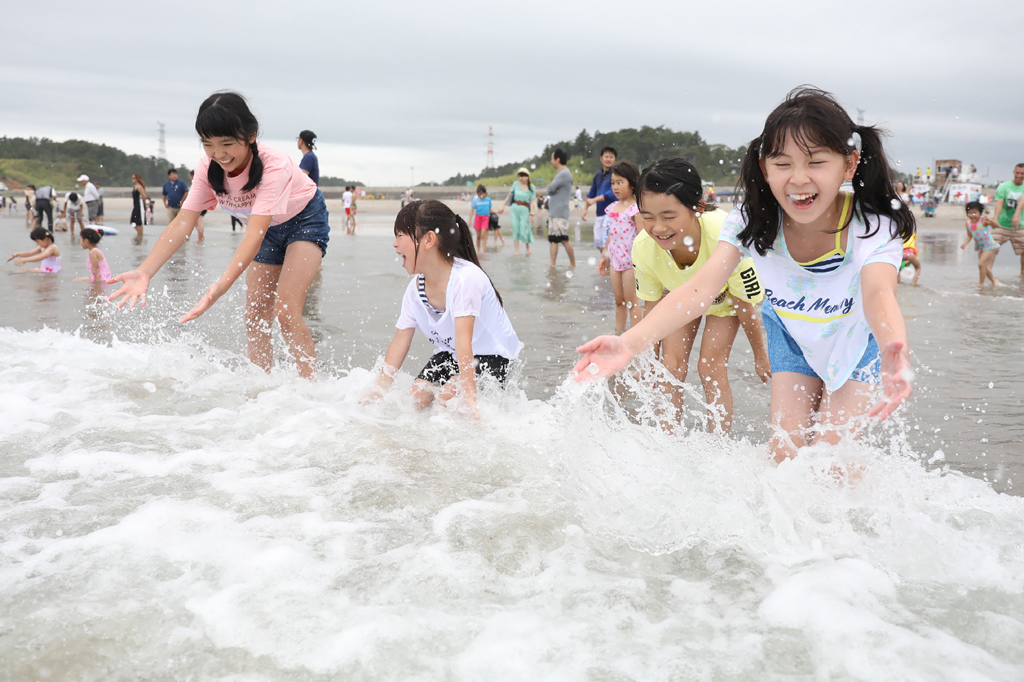Kinder spielen in den Wellen am 25 Kilometer von den Atomruinen von Fukushima entfernten Strand (Bild: Jiji Press/AFP)