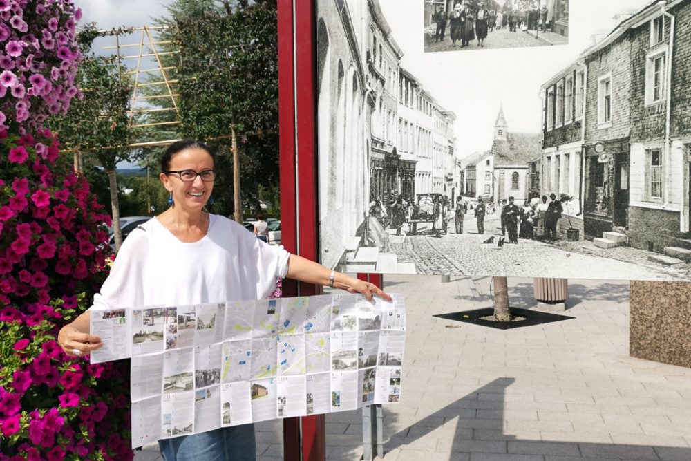 Andrea Theissen vom Tourist-Info St. Vith mit dem neuen Prospekt vor einer der historischen Tafeln (Bild: Rafaela Schaus/BRF)