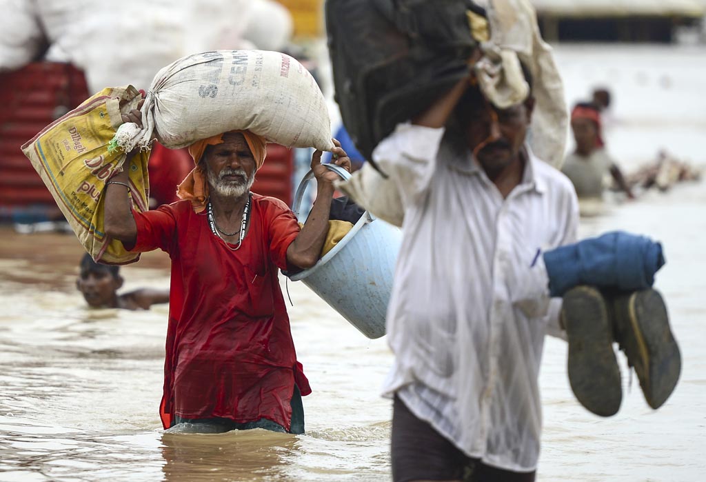 Menschen waten in Indien durchs Wasser (Bild: Sanjay Kanojia/AFP)